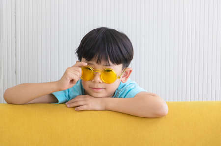 Portrait Asian cute boy.Child boy standing with yellow sofa in room.lovely,nice,development.photo concept knowledge and  Kid portrait.の写真素材