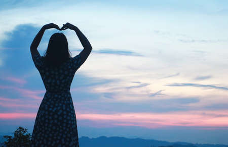 silhouette  Women standing on cliff and see over view in nature.She is raise hand up and enjoying...