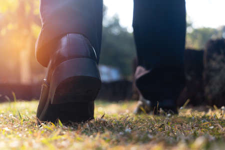 Close up business man walking on grass in public park. He is wearing black shoe and step up in to grass in a yard.good health,going, objective,Photo active and goal concept idea.の写真素材