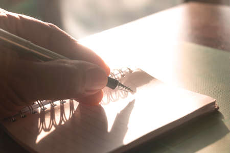 Close up human hand writing something on book in room.の写真素材