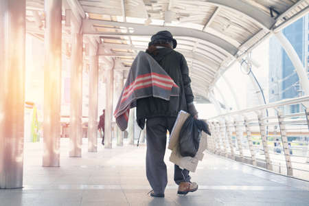 Homeless man is sitting down on walkway in town.He is very sadly and unhappy.poverty,despair,Photo Sympathetic and hope concept.の写真素材