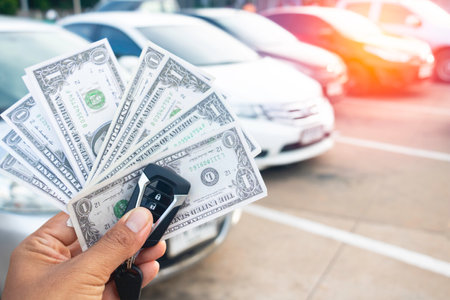 A hand holding a lot of dollars and car.A man holding dollars for cash on car.Money for sales exchange.money ,banknotes,exchange,finance .Photo concept buying car and money.の写真素材