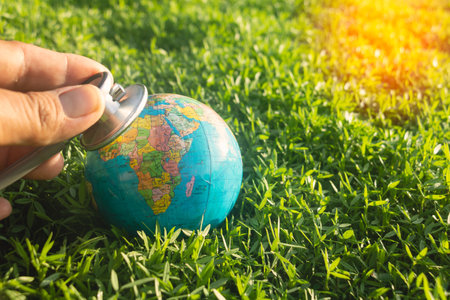 Hand and stethoscope with world on green grass.Hand holding stethoscope check on earth.Global warming, earth,Photo concept save world and good feel.の写真素材