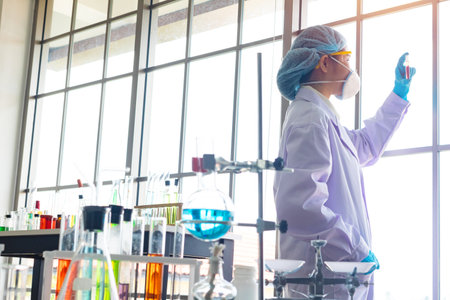 Body past scientist working in laboratory. She is looking in test tube. She is trying and research with blue test tube. Experiment, chemical. Photo concept develop and medicine.の写真素材