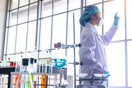 Body past scientist working in laboratory. She is looking in test tube. She is trying and research with blue test tube. Experiment, chemical. Photo concept develop and medicine.の写真素材