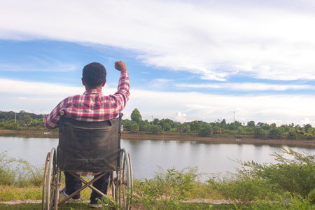 Young disabled man with river background.He is sitting on wheelchair and looking into river.despair,lonely,hope.Photo concept depression and Patient.の写真素材