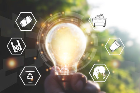 Hand holding light bulbs and icons global warming.Creative thinking ideas for work on desk.searching for new ideas,Knowledge,successful, wisdom.Photo concept of knowledge and education.の写真素材