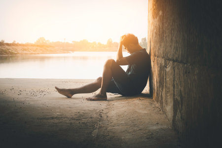 Asia you man sitting alone.He sitting in cave.man very sad and depressed.sad,alone,suicide,despair,sickness,photo health and disappointment concept.の写真素材