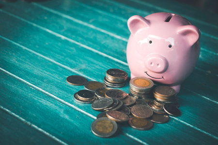 Saving  money.Pig piggy bank with icon finance on wood block.They are on blue blackground. save money.investment,bank,finance,Photo financial saving and Saving.の写真素材
