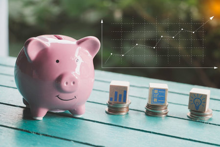 Saving  money.Pig piggy bank with icon finance on wood block.They are on blue blackground. save money.investment,bank,finance,Photo financial saving and Saving.の写真素材