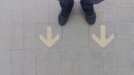 A man standing on âarrowâ word.He is wearing black Shout and standing on Metal floor. go,grow. Photo safe and  sign concept idea.の写真素材