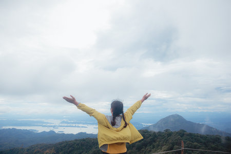Woman standing on cliff and see over view in nature. Tourist show  hands up and enjoying fresh air. A man enjoying free happiness in beautiful Thailand landscape.の写真素材