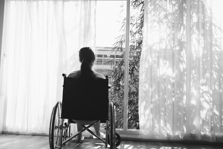 The woman sitting on wheelchair. She is see window with patient bed in hospital.disabled person lonely. Photo concept depression and Patient.の写真素材