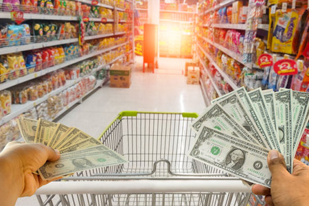 A hand holding dollars on shop. A man holding dollars for cash  on product background.Money for sales exchange. Photo concept  finances and money.の写真素材