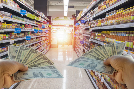 A hand holding dollars on shop. A man holding dollars for cash  on product background.Money for sales exchange. Photo concept  finances and money.の写真素材