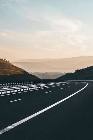 Empty highway with a beautiful sunset, blue sky and mountains in the background