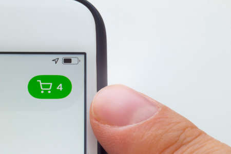 A person about to look a shopping cart on a phone and white background.のeditorial素材
