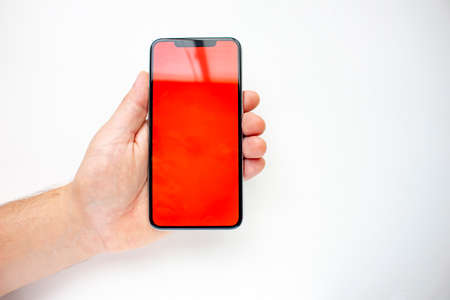 A person holding an Smart Phone with a red screen on a white background.の写真素材