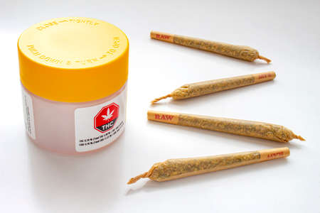 Calgary, Alberta, Canada. Aug 19, 2020. A Cannabis white and yellow plastic packaging container with Cigarettes, Prerolls or Joints on a white backgroundのeditorial素材