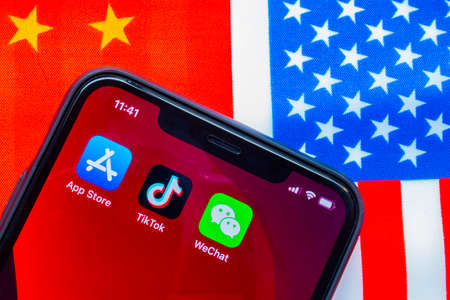 Calgary, Alberta, Canada. Sep 18, 2020. An iPhone with the App Store, TikTok and WeChat applications with a USA and China flag on the background. Concept Banning the chinese apps in USAのeditorial素材
