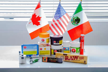 Calgary, Alberta, Canada. Sep 18, 2020. Canadian legal cannabis popular brands of marijuana weed plastic containers with USA, Mexico and Canada flag.のeditorial素材