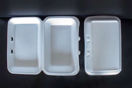 Top view of takeaway boxes, white foam boxes, rectangular shaped clamshell style container with an attached lid, on black backgroundの写真素材