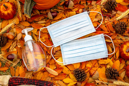 A bottle of a hand sanitazer and facemask on a halloween and thanksgiving background. Concept:...