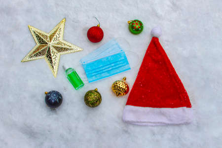 Christmas ornaments decorations and a face masks on snow. Concept: Covid-19, coronavirus during...