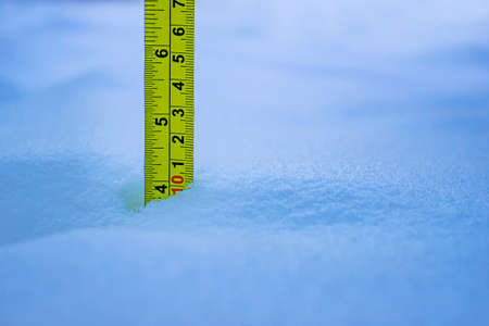 Measuring the snow depth with yellow ruler 10 Centimetersの写真素材