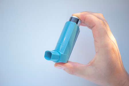 A person holding an asthma inhaler on a clear background