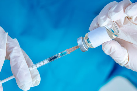 A health worker holding a syringe and a vial vaccine, getting it fill with medicine.の写真素材
