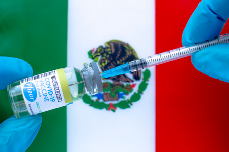 Calgary, Alberta. Canada. Jan 20, 2021. A health worker with a Pfizer vaccine and a syringe with a Mexican flag on the backgroundのeditorial素材