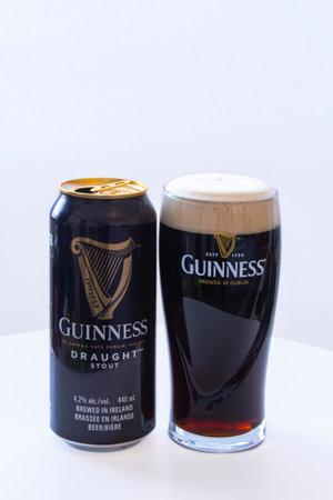 Calgary, Alberta, Canada. March 12, 2021. A Can of Guinness with a Pint of Beer draught on a white...