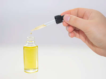 A person dropping cannabis oil on an transparent bottle on clear background.の写真素材