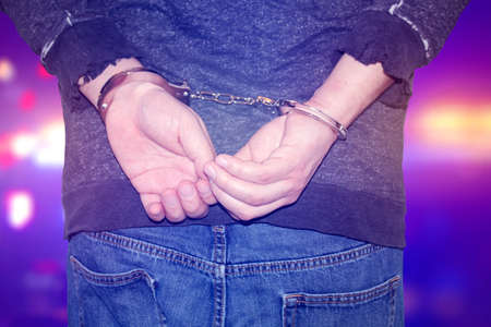 A person on handcuffs, male hands criminal with handcuffs.