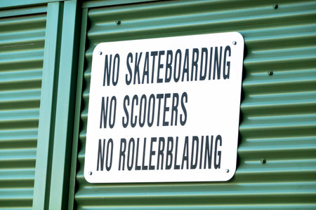 A sign with the text No Skateboarding, No Scooters, No Rollerblading on a metal wall.の写真素材