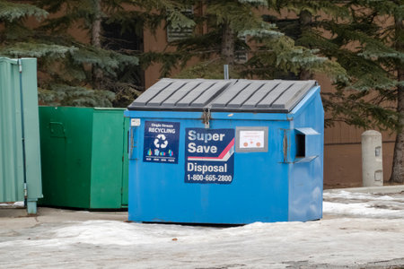 Calgary, Alberta, Canada. Feb 19, 2023. A blue garbage dumpster of recycle waste during the winter.のeditorial素材