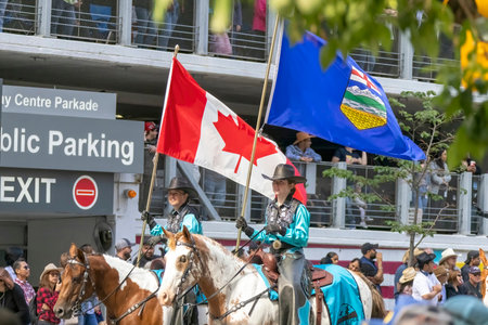 Calgary, Alberta, Canada. July 7, 2023.A couple of people riding horses holding a Canadian flag an Alberta flagat a public parade.のeditorial素材