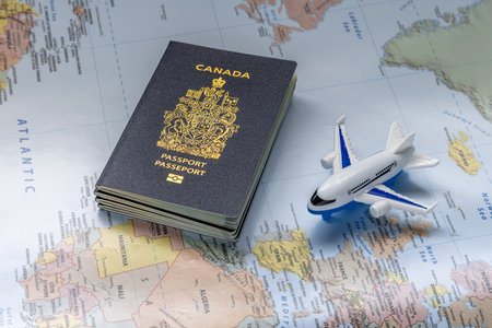 Calgary, Alberta, Canada. Aug 3, 2023. Canadian passport next to an airplane on a world map. Concept: Canadians traveling abroad.のeditorial素材