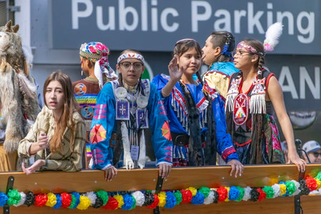 Calgary, Alberta, Canada. July 7, 2023. Close up to a young First Nations teens wearing traditional cloths while riding on a carriage at a public festival parade.のeditorial素材