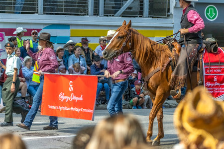 Calgary, Alberta, Canada. July 7, 2023. Some people holding a Calgary Stampede sign at a public parade.のeditorial素材