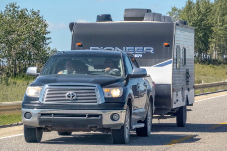 Cochrane, AB, Canada. Aug 13 ,2023. A close up to a pickup truck towing a RV trailer camper during summer on a highway.のeditorial素材