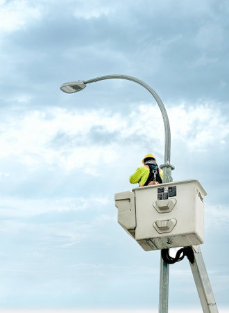 Calgary, Alberta, Canada. Feb 9, 2024. An aerial work platform and a Hi-Ranger Overcenter Aerial Device featuring a bucket for efficient utilities operations with a worker fixing lights.のeditorial素材
