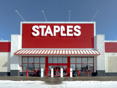 Calgary, Alberta, Canada. Feb 25, 2024. The entrance structure of a Staples store amid winter, set against a backdrop of a clear blue sky.のeditorial素材
