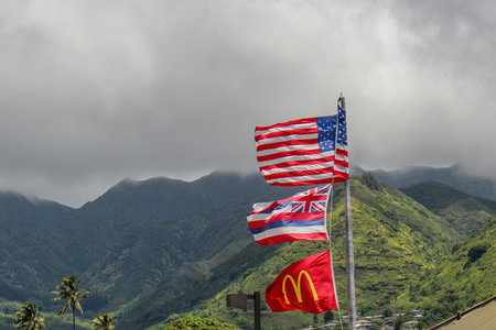 Honolulu, Hawaii, USA. Apr 20, 2014. Flags of the United States, Hawaii, and McDonald's waving in the wind on a breezy day. In the BG, the silhouette of Hawaiian mountains against a cloudy sky.のeditorial素材