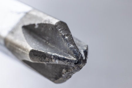 A close-up of a worn, metallic phillips head screwdriver with a flattened tip and visible wear marks.の写真素材
