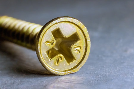A yellow screw head, partially embedded in a surface, showcases its serrated edges and a subtle marking.の写真素材