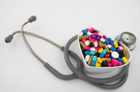 Colorful pills and capsule in a cup and Stethoscope on white backgroundの写真素材