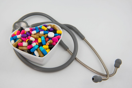 Colorful pills and capsule in a cup and Stethoscope on white backgroundの写真素材