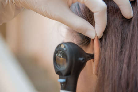 woman doctor monitors the patient's ear with equipmentの写真素材